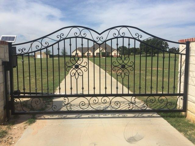Custom ornamental iron estate entry gate with scrollwork leading to a home in Decatur, TX