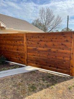 Reddish-stained horizontal cedar privacy fence with matching gate in Decatur, TX