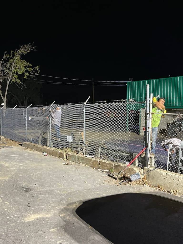 Affordable Fencing crew installing commercial chain link fence at night
