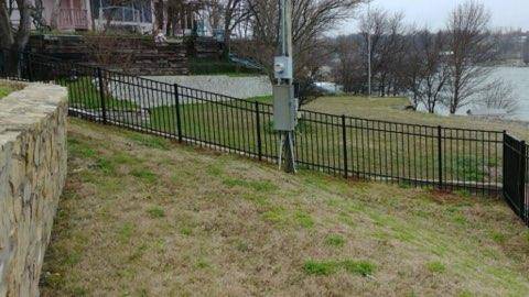 Ornamental iron fence along a lakeside stone retaining wall near Decatur, TX