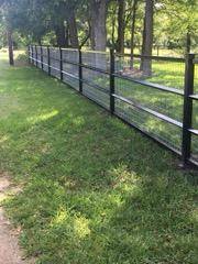 Black pipe and wire perimeter fence along a tree line in Wise County